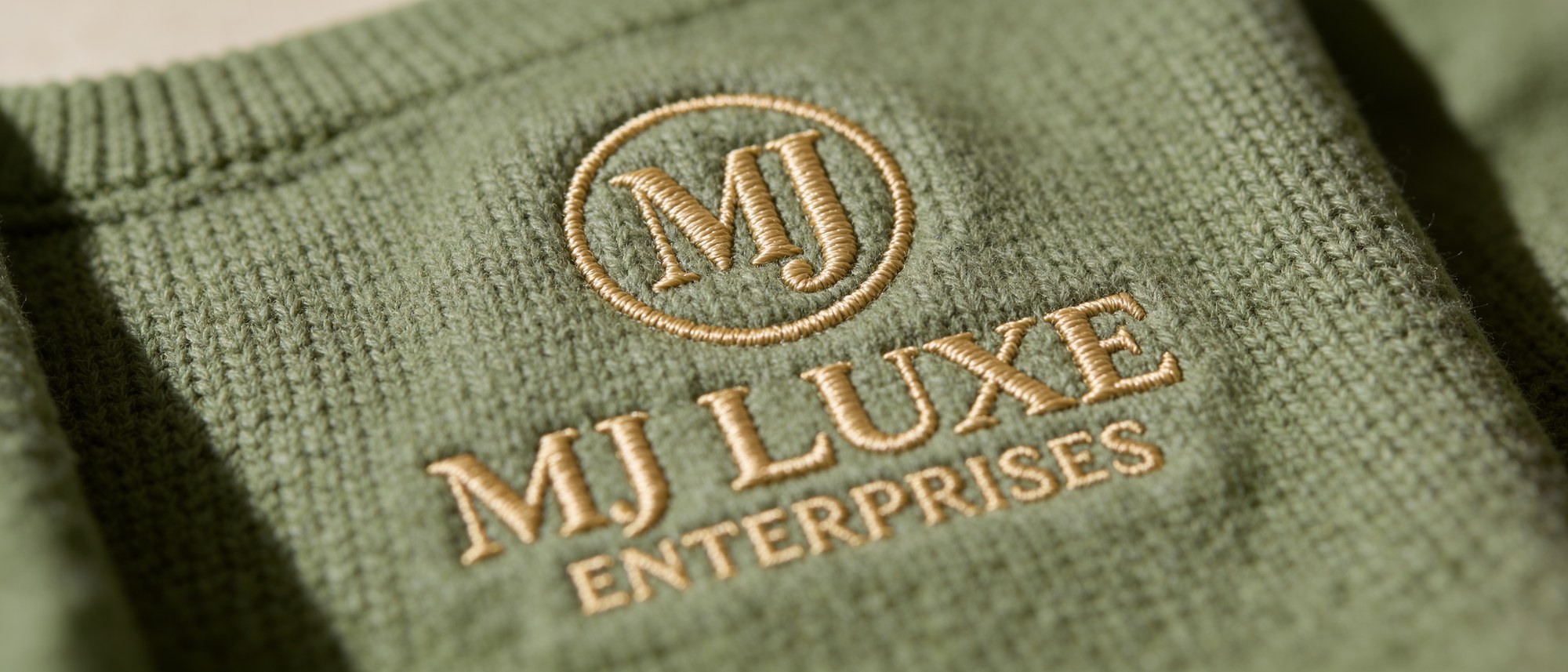 Close-up of the MJ Luxe logo embroidered into premium knit fabric